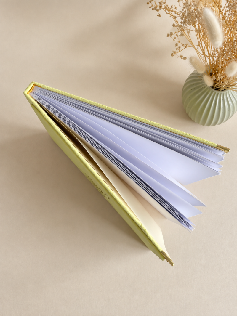 Kollane sametine fotoalbum valgete lehtede, kuldsete nurgakaitsmete ja minimalistliku lillemustriga kaanel.